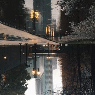 A photograph of a city street, showing the reflection on the pavement right side up, and the city beneath it.